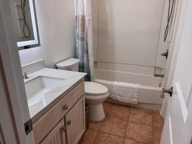 Modern bathroom with marble vanity, tub, and wave shower curtain