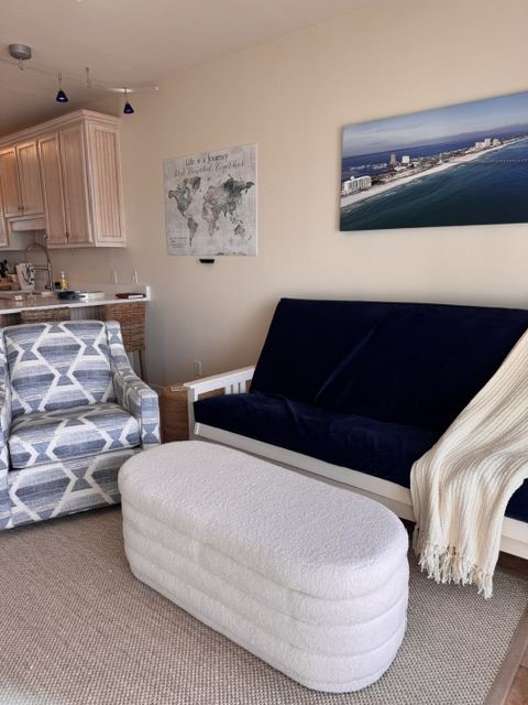 Cozy living space with sofa, ottoman, and coastal wall art