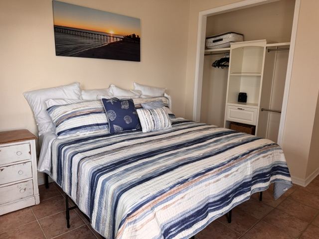 Primary bedroom with king bed, striped bedding, and coastal pier artwork
