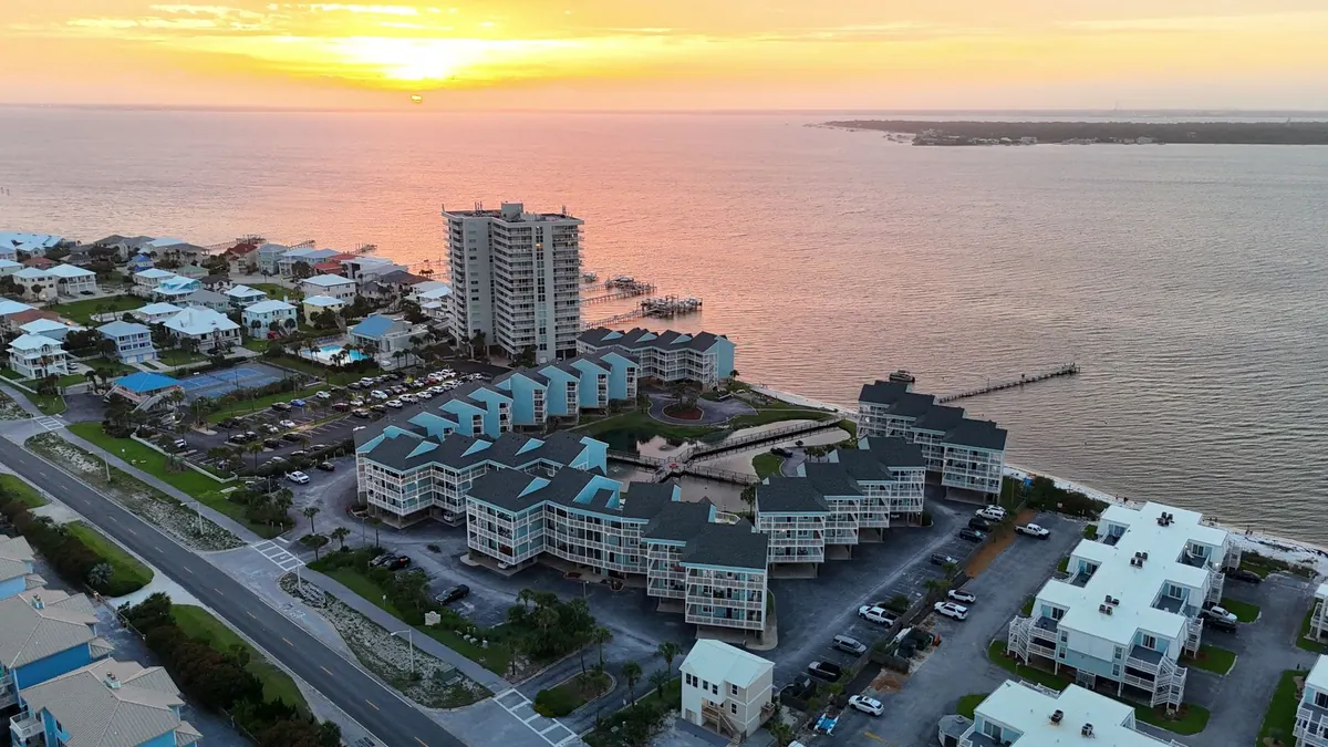 Aerial sunset view of the community, beach, and pier