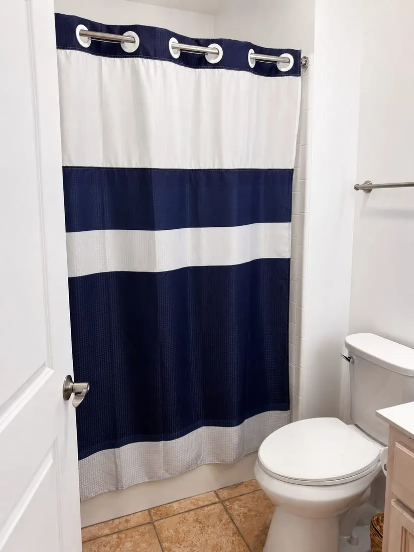 Bathroom vanity with lit mirror and navy shower curtain